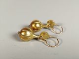 pair of gold tone earrings on a white surface