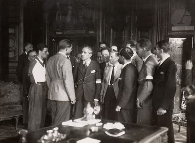 many men standing in a room talking to each other