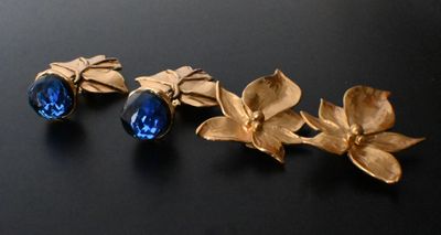 two pairs of gold and blue crystal earrings on a black surface