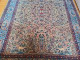 un grand tapis persan posé sur un parquet dans un salon