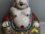 une petite statue représentant un Bouddha souriant, posée sur une table