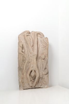 sculpture représentant un visage sur un bloc de pierre dans une pièce blanche