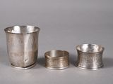 trois tasses en argent posées l'une à côté de l'autre sur une table
