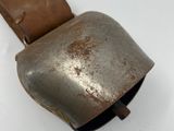 an old metal bell with a leather strap on it