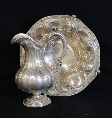 an antique silver plate with a silver pitcher on a black background