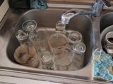a sink filled with dirty dishes and empty glasses