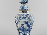 a blue and white vase with a bird on top of it