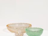 two glass bowls sitting on top of a white pedestal