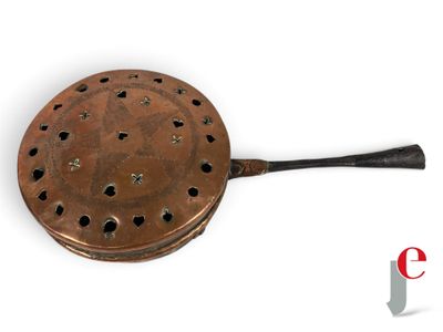 an old copper frying pan with a handle and holes in it