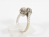 a close up of a ring with two diamonds on a clear base