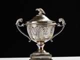 a silver cup with a bird on it sitting on top of a table
