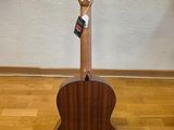 an acoustic guitar stands on a hard wood floor in front of a white wall