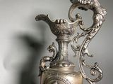 a silver vase that has a bird on top of it