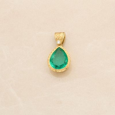 an image of a gold pendant with a green tear shaped stone