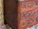 a wooden chest of drawers in a room with a floral wallpaper