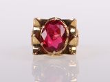 a close up of a gold ring with a red stone