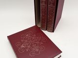 two red books sitting next to each other on a white surface