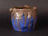 a blue and brown vase on a black surface