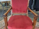 an old wooden chair with red velvet upholstered on top of a rug