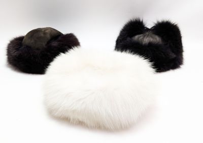 deux bonnets en fourrure noirs et blancs posés sur une surface blanche