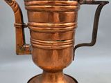 an antique copper coffee pot with a bird on top