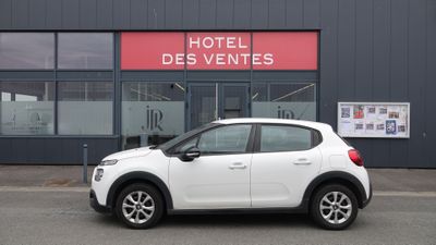 une petite voiture blanche garée devant un hôtel