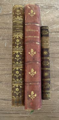 trois vieux livres sont empilés les uns sur les autres sur une table en bois