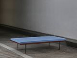 a blue bench sitting on a wooden floor next to a wall