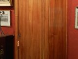 a tall wooden cabinet in a room with pictures on the wall