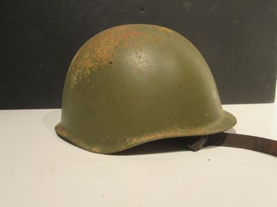 un vieux casque vert posé sur une table, à côté d'une tasse