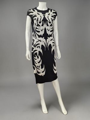 une robe noire et blanche avec des broderies dorées sur les épaules