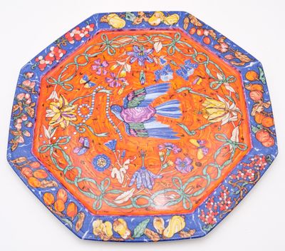 an orange and blue plate with a bird and flowers design on it