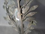 a metal sculpture of a plant with leaves and a bird on top of it