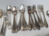 a lot of silver spoons and forks laid out on a table