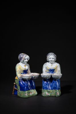 two figurines of two women sitting on a black surface