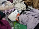 a pile of clothes and a pair of shoes on a bed