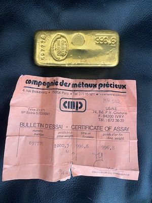 un lingot d'or et un certificat posés sur un sac en cuir noir, sur une table