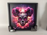 two framed pictures of a skull and flowers on a table