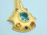 a gold brooch with a green stone on it
