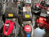 Plusieurs tondeuses à gazon sont alignées en rang dans un garage