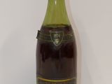 une vieille bouteille de vin posée sur une table blanche