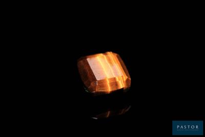 un gros plan d'une bague posée sur une surface noire, avec un fond noir