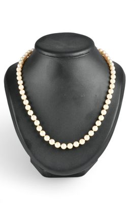 un collier de perles blanches sur un mannequin avec un fermoir en or