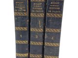 three old books sitting on top of each other on a white surface