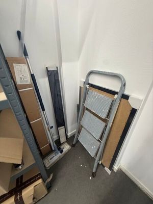 a pile of boxes and a ladder in the corner of a room