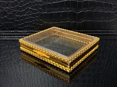 une boîte en or contenant un miroir sur une surface noire