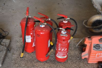 Plusieurs extincteurs sont alignés sur le sol, à côté d'une borne d'incendie