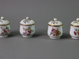 three small porcelain jars with floral designs on them on a gray surface