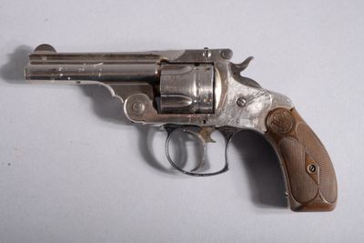 un vieux revolver avec une poignée en bois sur une surface blanche
