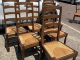 four wooden chairs sitting in a parking lot next to a white car
